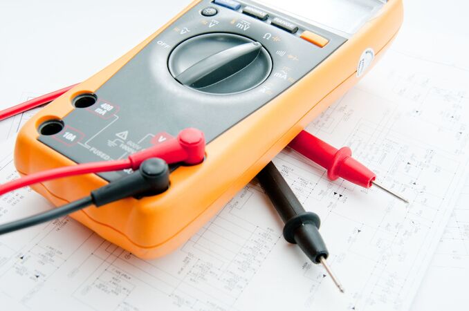 Digitalmultimeter mit Messleitungen liegt auf technischem Schaltplan für Elektronik.